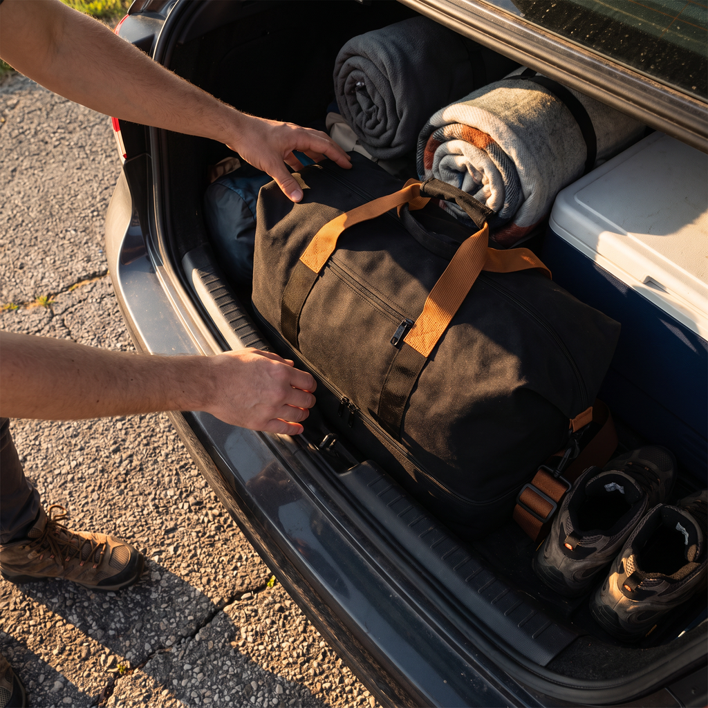 Weekender Duffle Bag (Black) being packed into a car trunk for a road trip